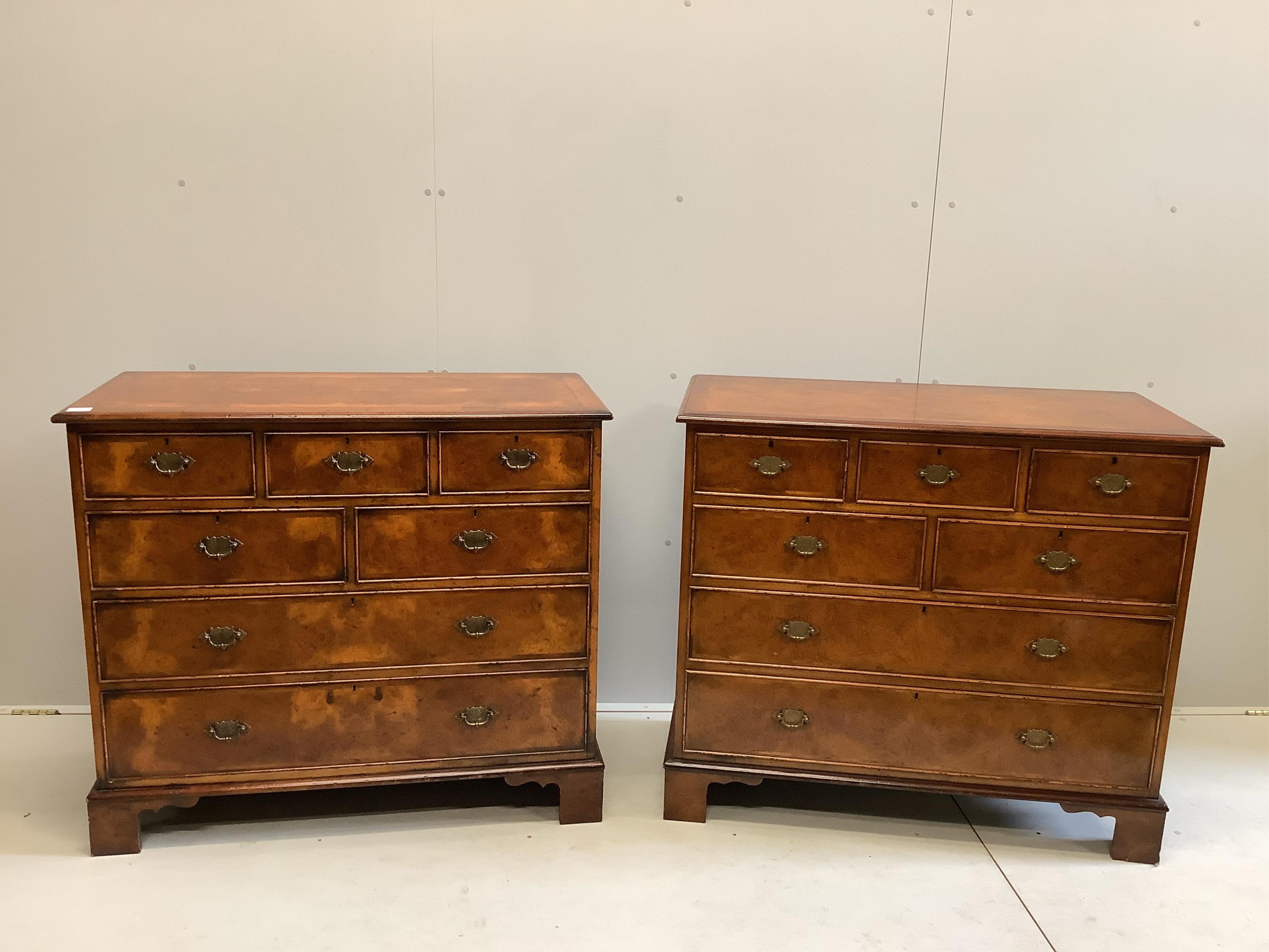 A pair of reproduction George I style feather banded walnut chests of drawers, width 104cm, depth 50cm, height 91cm